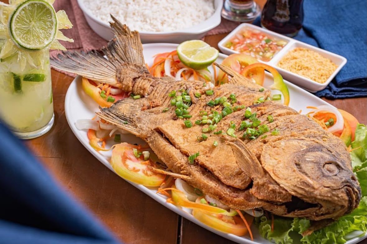 Peixe inteiro frito com salada, vinagrete, farofa e caipirinha